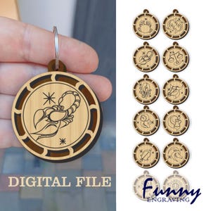 Może przedstawiać: Drewniane breloczki do kluczy ze znakami zodiaku. Breloczki mają okrągły kształt z jasnobrązowym środkiem i ciemnobrązową obwódką. Na zdjęciu widnieje breloczek ze wzorem skorpiona i napisem "DIGITAL FILE". Pokazano również inne breloczki z różnymi znakami zodiaku.