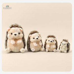 May include: Four plush hedgehog toys of different sizes. They have soft, beige bodies, brown spiky backs, and small, light pink ears. The toys are arranged from largest to smallest. The background is a plain, light beige colour.