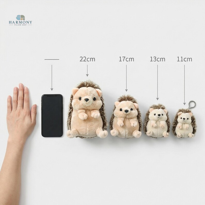 May include: Four plush hedgehog toys of different sizes are shown, ranging from 11cm to 22cm in height. The hedgehogs have soft, beige bodies, brown fur, and small, dark eyes. A smartphone is placed next to the largest hedgehog for size comparison.