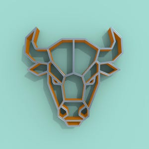 Puede incluir: Una decoración de pared con forma de cabeza de toro geométrica que presenta un marco metálico plateado con acentos interiores de color naranja vibrante. La estructura se compone de líneas angulares que forman la silueta de un toro.