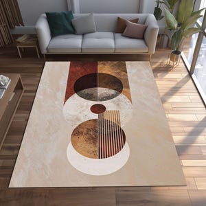 May include: A rectangular area rug with a geometric design in shades of beige, brown, and rust. The rug features abstract shapes including circles, ovals, and vertical lines. The rug is placed on a hardwood floor, with a sofa and plants in the background.