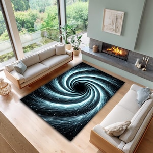 May include: A rectangular area rug with a swirling black hole design. The rug features a black center with radiating blue and white lines, creating a vortex effect. The rug is placed on a wooden floor, with two beige sofas and a fireplace in the background.