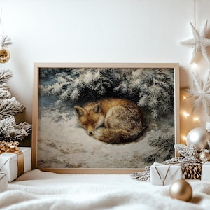 May include: A framed rectangular wall art print featuring a realistic painting of a red fox curled up and sleeping in the snow beneath snow-covered evergreen branches. The artwork is displayed in a light-coloured wooden frame with a clean border.