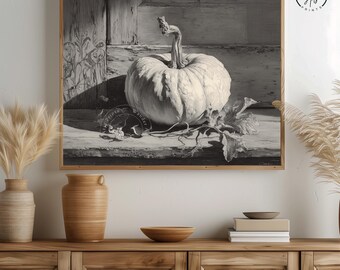 May include: Black and white framed print of a white pumpkin with a curved stem, resting on a wooden surface. The print includes leaves and the text "Wander Arts". The artwork is in a wooden frame.
