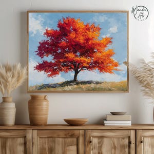Pode incluir: Uma impressão artística emoldurada de uma árvore vermelha vibrante com uma copa cheia, contra um céu azul claro com nuvens brancas. A obra de arte é exibida em um armário de madeira com vasos e tigelas decorativas.