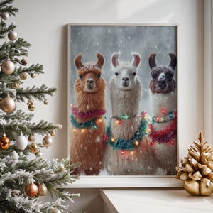 May include: A framed print featuring three llamas adorned with festive garlands and string lights, set against a snowy backdrop. The llamas, in shades of brown, white, and dark brown, are decorated for the holidays. A Christmas tree and gold ornament are in the foreground.