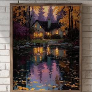 May include: A framed painting depicts a serene landscape with a house by a lake. The house has lit windows, reflecting in the water. Autumn foliage in shades of gold, orange, and purple surrounds the house, creating a warm, inviting scene.
