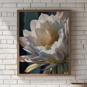 May include: A framed floral print featuring a close-up of a large, white cactus flower with delicate petals. The flower has a yellow center and is set against a dark background. The wooden frame adds a natural touch.
