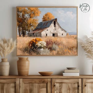 May include: A framed landscape painting depicting a weathered white barn with a rusted roof set in a golden field. The scene includes autumn-colored trees and a cluster of orange and white flowers in the foreground under a pale blue sky.