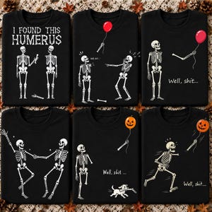 Könnte beinhalten: Eine Kollektion aus sechs schwarzen Sweatshirts mit Rundhalsausschnitt und weißen Skelettgrafiken. Die Designs zeigen Skelette mit Knochen, roten Luftballons und Kürbissen, ergänzt durch den Text I FOUND THIS HUMERUS und Well, shit.