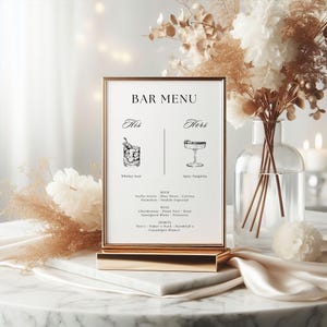 Puede incluir: Un men&uacute; de bar con marco dorado con el texto "BAR MENU" en la parte superior. El men&uacute; presenta ilustraciones de un Whiskey Sour y una Spicy Margarita, con opciones de bebidas enumeradas a continuaci&oacute;n. El men&uacute; se muestra sobre una superficie de m&aacute;rmol con arreglos florales.