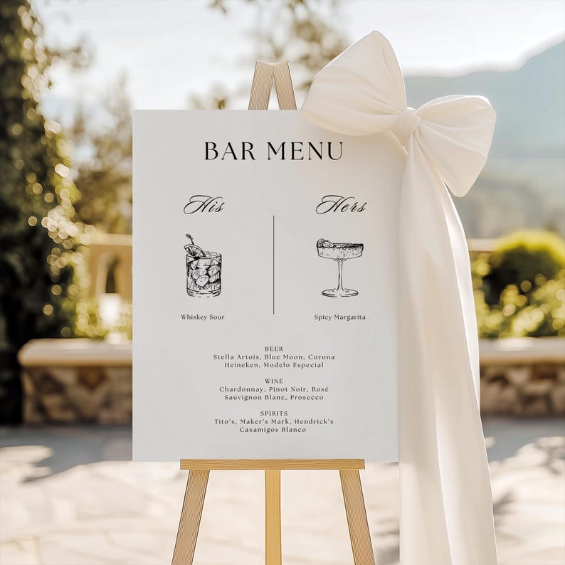 Puede incluir: Un letrero blanco de men&uacute; de bar sobre un caballete de madera, con opciones de bebidas "His" y "Hers". El letrero incluye ilustraciones de Whiskey Sour y Spicy Margarita, con una lista de cervezas, vinos y licores. Un gran lazo blanco adorna el caballete.
