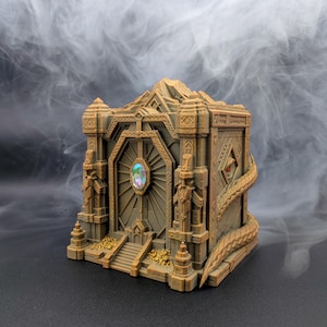 Puede incluir: Una caja rectangular de color bronce diseñada como una puerta de fortaleza con detalles arquitectónicos intrincados, una gema ovalada iridiscente en el centro, pequeños montones de monedas doradas en la base y una larga cola de dragón.