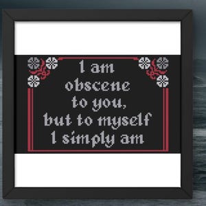Puede incluir: Arte de punto de cruz enmarcado con la cita "I am obscene to you, but to myself I simply am." El texto blanco sobre fondo negro, con detalles florales rojos y blancos. El marco es negro.