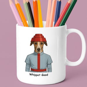 May include: White ceramic mug with a cartoon whippet in a red hat and blue uniform, holding colourful pencils. The mug has the text "Whippet Good". The pencils are in various colours.