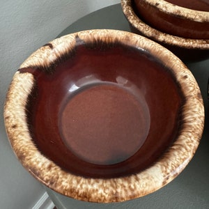 May include: A brown and white glazed ceramic bowl with a brown interior. The bowl has a speckled glaze pattern.