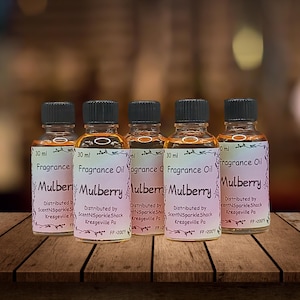 Puede incluir: Cinco peque&ntilde;os frascos de vidrio de aceite de fragancia de mora, cada uno con 30 ml. Los frascos tienen tapas negras y etiquetas con las palabras "Mulberry" y "Fragrance Oil". Las etiquetas tambi&eacute;n incluyen el nombre y la ubicaci&oacute;n del distribuidor.