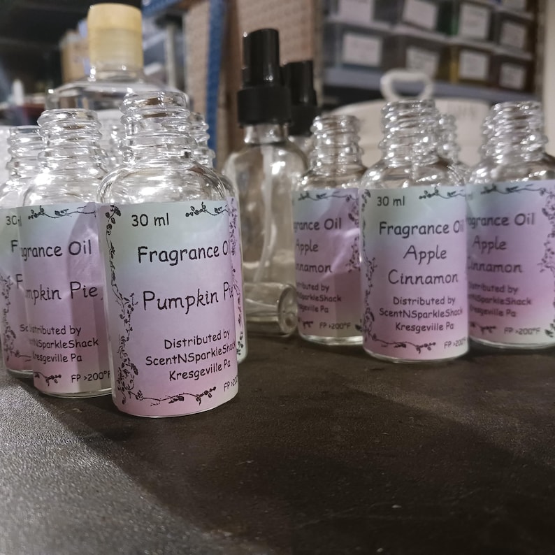 Puede incluir: Una colecci&oacute;n de botellas de aceite de fragancia de vidrio transparente con etiquetas. Las etiquetas muestran los nombres de las fragancias "Pumpkin Pie" y "Apple Cinnamon". Cada botella contiene 30 ml de aceite. Las botellas est&aacute;n dispuestas sobre una superficie.