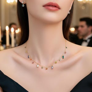 Puede incluir: Un collar de oro y pendientes a juego con detalles de piedras preciosas de colores. El collar presenta una delicada cadena con piedras preciosas de varias formas y colores. Los pendientes tienen una sola piedra preciosa.