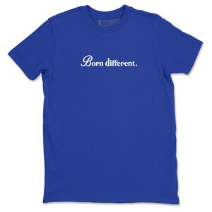 Op de afbeelding: Koningsblauw T-shirt met de witte tekst "Born different." Het shirt met korte mouwen heeft een ronde hals en is gemaakt van een zacht materiaal. De tekst is in een cursief lettertype.