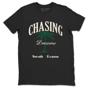 Puede incluir: Camiseta negra con un diseño gráfico. El diseño incluye las palabras "CHASING Dreams" sobre una ilustración de palmera verde. Debajo, el texto dice "Never settle. It's a process."