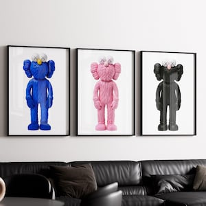 Peut inclure: Trois impressions d'art encadrées représentant des personnages de dessins animés stylisés en bleu, rose et noir. Chaque personnage a des yeux blancs en forme de X et une tête blanche. Les impressions sont affichées au-dessus d'un canapé sectionnel en cuir noir.