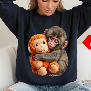 May include: Navy blue sweatshirt featuring a detailed graphic of two monkeys hugging. One monkey is orange and plush, the other is realistic. The image is labeled "Ultra Detailed" and "PNG DIGITAL DOWNLOAD".
