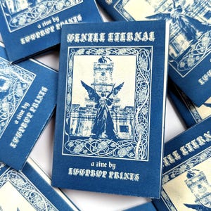 May include: A collection of blue and cream zines titled Gentle Eternal, a zine by Eggprop Prints. Each cover features a central illustration of a winged figure standing before a tall structure, framed by an intricate border of vines and flowers.