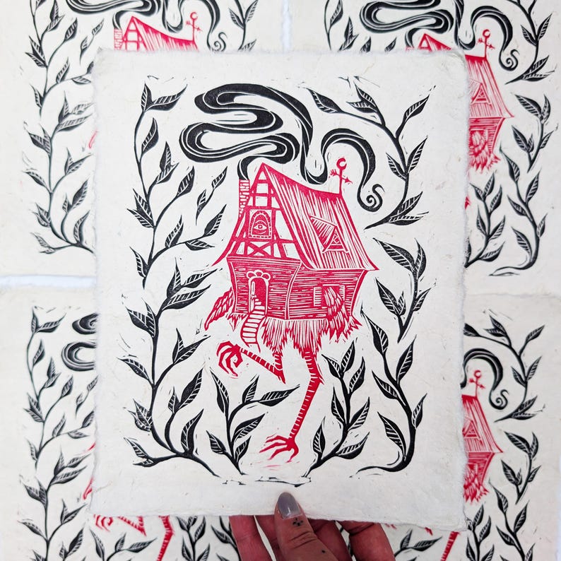 May include: A red and black linocut print of a whimsical house with legs, surrounded by leafy vines. The house has a chimney with swirling smoke and an eye symbol. The print is on textured, off-white paper.
