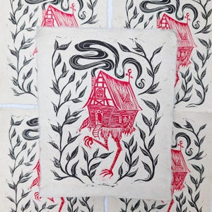 May include: Red and black linocut print of a house with legs, surrounded by black leafy vines. The house has a red roof, chimney smoke, and a door. The print is on textured, off-white paper.