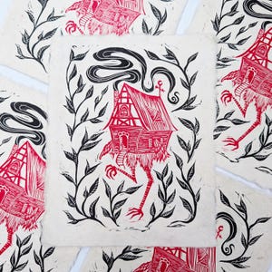 May include: Red and black linocut print of a house with legs, surrounded by black leafy vines. The house has a red roof, chimney smoke, and a key above the door. The print is on textured, off-white paper.