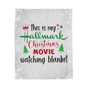 Könnte beinhalten: Weiße Decke mit dem Text "this is my Hallmark Christmas movie watching blanket" in Grün, Rot und Schwarz. Das Design umfasst eine Krone, Schneeflocken und Weihnachtsbäume.