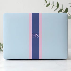 May include: A light blue laptop skin featuring a vertical design with a central dark blue stripe flanked by two light pink stripes. The letters HS are printed in a light pink serif font in the center of the dark blue stripe on the laptop cover.