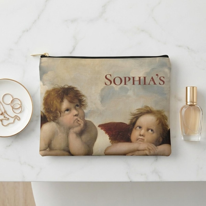 May include: A zippered pouch featuring a Renaissance-style painting of two cherubs with red wings against a cloudy sky. The name "SOPHIA'S" is printed in maroon. The pouch has a black zipper and trim.
