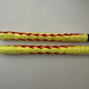 May include: Two glitter pens with yellow barrels and red arrow designs. The pens have black tips and silver accents. The pens are approximately 6 inches long.