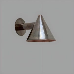 May include: A modern wall sconce with a conical shade. The fixture is made of metal with a dark, metallic finish. The shade has a copper-colored interior, and the sconce is mounted on a circular base.