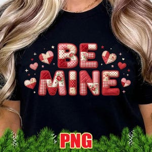 Puede incluir: Camiseta negra con las palabras "BE MINE" en un diseño de patchwork. Las letras son en tonos rojos y rosas, con estampados florales y de cuadros. Pequeños corazones y estrellas rodean el texto.