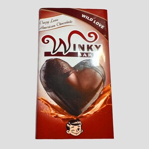 May include: A Winky Bar chocolate bar with a heart-shaped chocolate center. The packaging is red and features the words "Crazy Love American Chocolate" and "Wild Love". A cartoon boy winking is at the bottom.