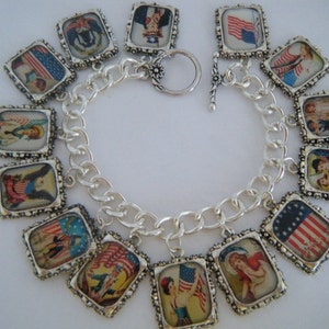 Puede incluir: Un brazalete de plata con múltiples dijes que presentan imágenes patrióticas, incluyendo banderas, ángeles y personas. Los dijes son de plata con un borde texturizado y presentan imágenes coloridas.