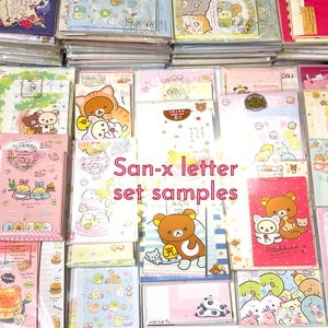 May include: A collection of San-x letter set samples, featuring various designs with cartoon characters. The sets include stationery items like notepads and envelopes, in a variety of colors including pink, blue, and yellow. The text "San-x letter set samples" is visible.