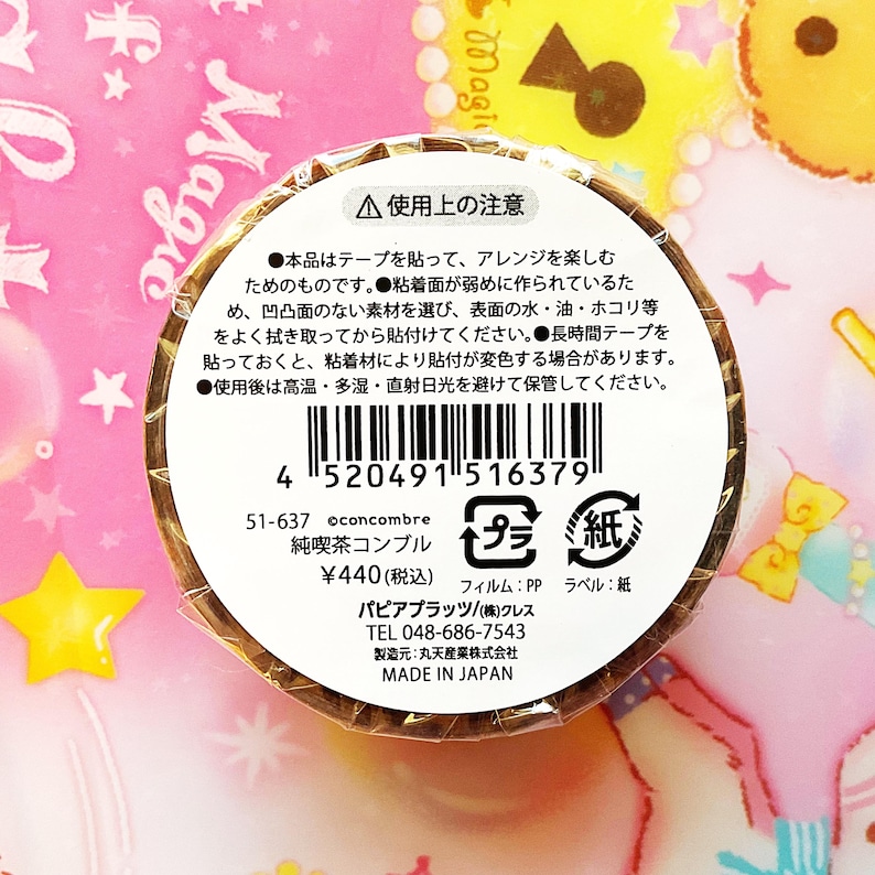 May include: A roll of decorative tape with a brown, textured exterior. The label includes Japanese text, a barcode, and the text "MADE IN JAPAN". The tape is designed for arranging and decorating.