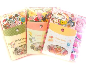 May include: A collection of colorful sticker packs, each with a unique design. The packs feature various themes, including food, animals, and other cute illustrations. The text "Flake Seal" is visible on the packaging.