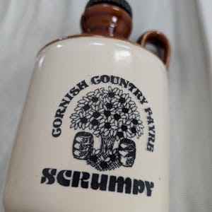 Könnte beinhalten: Cremefarbener Keramikkanne mit braunem Deckel und Griff. Die Kanne hat eine schwarze Grafik eines Baumes mit Fässern und den Text "Cornish Country Fayre" und "Scrumpy".