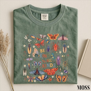 A green t-shirt with a colorful graphic design featuring various insects and butterflies, along with the text "Be kind to all kinds".