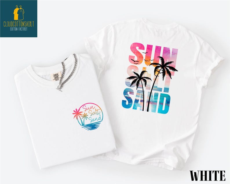 a white t-shirt with a colorful graphic design on the back, depicting a beach scene with palm trees and a sunset.
