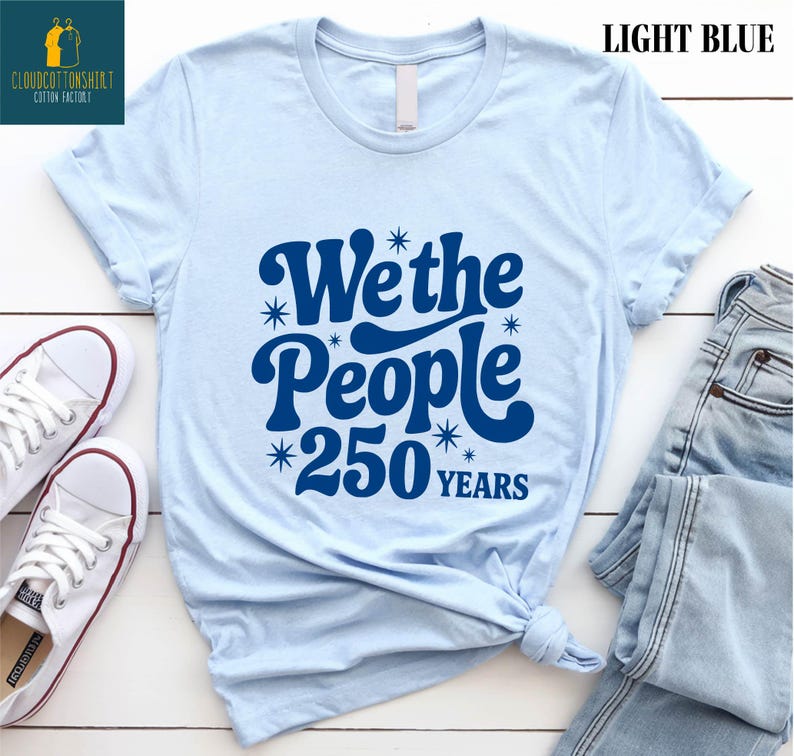 A light blue t-shirt with a graphic design that says "We the People 250 Years" printed on it, along with some jeans and white sneakers.