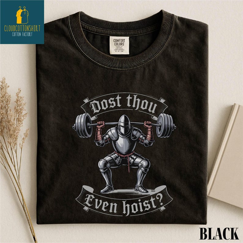 A black t-shirt with a graphic design depicting a knight lifting a barbell, accompanied by the text "Do you even hoist?"