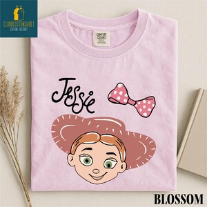 A pink t-shirt with a cartoon character and a pink polka dot bow, along with the text " Jessie" and "Blossom".