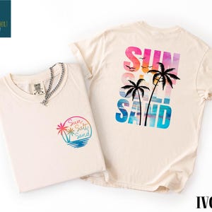 two t-shirts with beach-themed designs, including palm trees and a sunset.