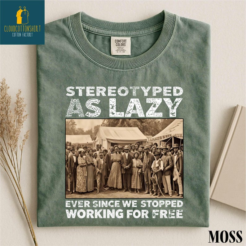 May include: Moss green t-shirt with the text "STEREOTYPED AS LAZY EVER SINCE WE STOPPED WORKING FOR FREE" in white. The shirt features a sepia-toned image of a group of people. The shirt has a Comfort Colors tag.